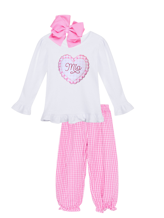 Children's outfit with white top, pink checkered pants, and large pink bow on a white background